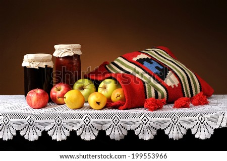 Fresh fruit in a bag of wool and jam in a jar on the table