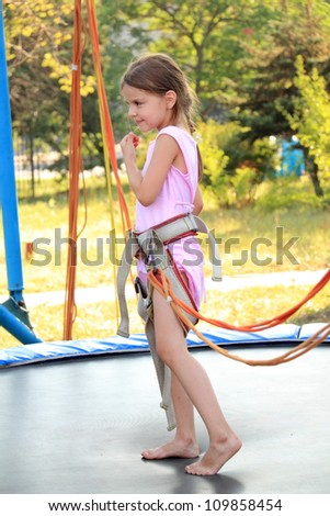 Little girl jumping on the trampoline (bungee jumping).
