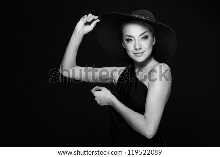 A black and white image of a beautiful young woman wearing stylish black hat on Beauty and Fashion theme