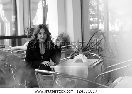 Outdoor black and white photography of smiley attractive young woman in street cafe on Food and Drink theme