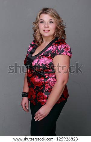 Smiley face of lovely adult woman with nice curly hair on Beauty and Fashion theme/Pretty woman wearing black and pink clothes and posing over dark gray background