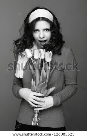 Studio black and white image of young woman with tulips/Cheerful beautiful young girl with a bouquet of spring flowers