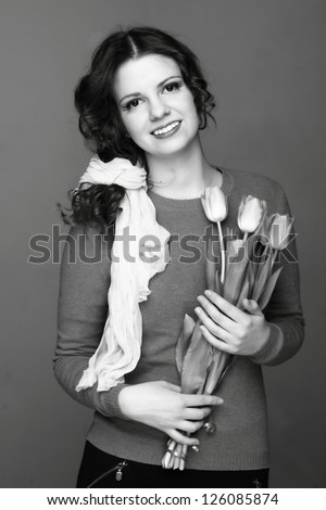 Black and white image of young cheerful european woman with tulips