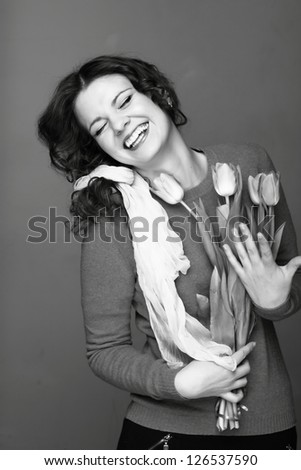 Studio black and white image of beautiful young woman with fresh tender tulips/Smiley young girl with a bouquet of spring flowers