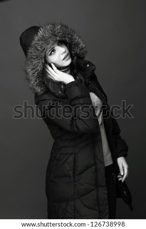 Black and White portrait of trendy young woman wearing warm clothes and enjoying modern music