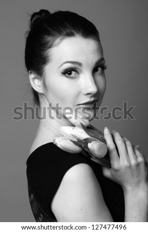 Studio black and white image of pretty young woman with fresh tender tulips