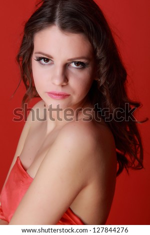 Emotional young woman wearing red dress over bright red background