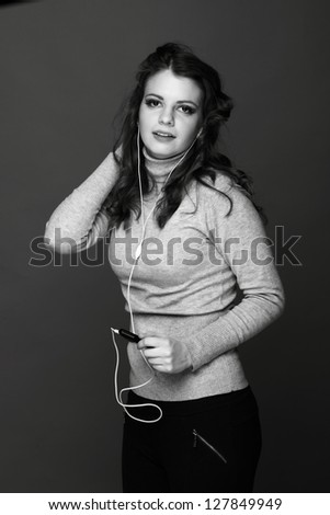 Black and White portrait of caucasian young woman wearing warm clothes enjoying modern music