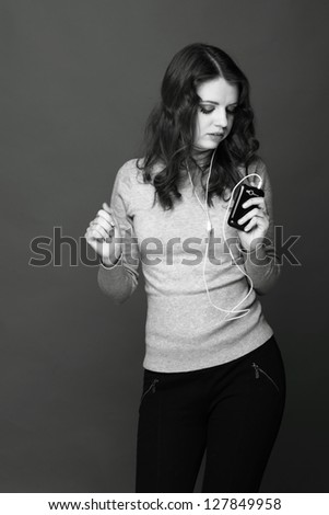 Black and White portrait/Beautiful caucasian young woman wearing warm clothes enjoying modern music