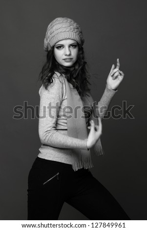 Black and White portrait of trendy teenage girl listening music by headphones/Studio portrait of beautiful caucasian young woman wearing warm clothes enjoying modern music