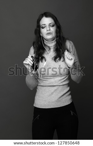 Black and white photo of emotional girl  with telephone listening to music and dancing