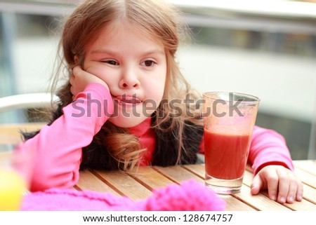 Funny girl at cafe indoor/Cute baby drinks tomato juice in cafe