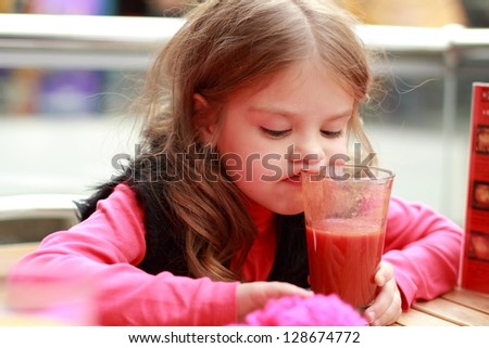 Funny girl at cafe indoor/Cute baby drinks tomato juice
