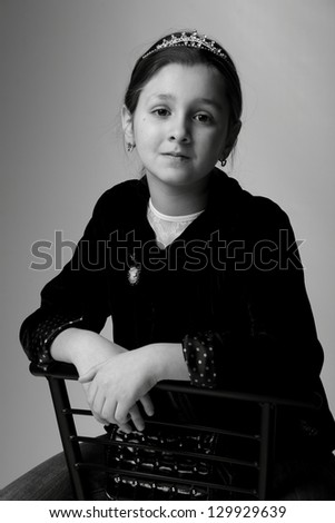 Black and white photography pretty little girl/Cute child in casual clothes sitting on a chair