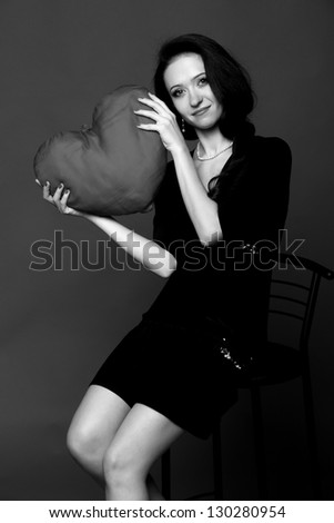 Black and white portrait of a sexy girl in a black dress holding a big heart
