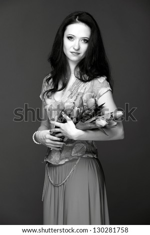 Black and white image of a beautiful woman with long healthy hair holding a bouquet of tulips