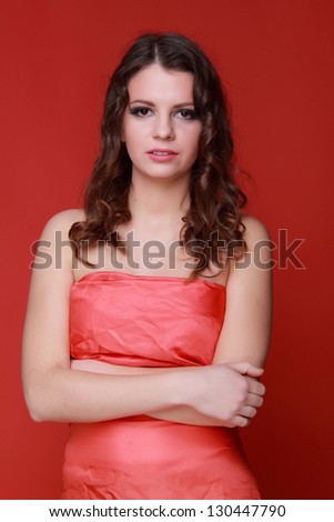 Adorable young girl with sad smile on red background