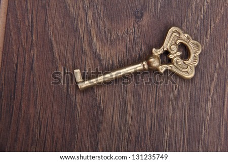 Old beautiful key with ornament on wooden background/Ancient metal key