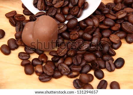 Cup with coffee beans and chocolate candies on wooden background on Food and Drink