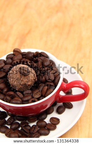 Coffee cup with heart symbol full of raw coffee beans and chocolate