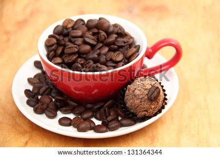 Red cup with heart symbol full of raw coffee beans and chocolate on Food and Drink theme