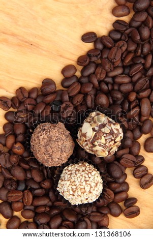 raw coffee beans and chocolate sweets on old light brown wooden table