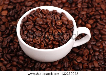 White mug full of coffee beans and ground coffee beans on Food and Drink