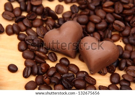 Lots of coffee sweets in shape of heart and coffee beans spilling on wooden background
