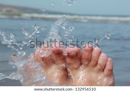 Bare feet in the water of the sea and the spray