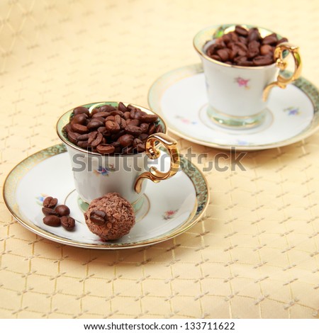 Two beautiful coffee cups with coffee beans and dessert on a beige tablecloth on food and Drink