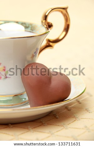 White coffee cup full of coffee beans and chocolate candy on the beige tablecloth on Food and Drink