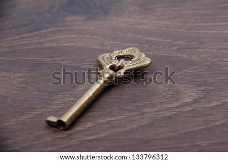 Beautiful vintage key on a patterned wooden background/Antique metal key