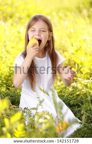Caucasian young girl with a sweet smile keeps fresh lemons on the street in the sunlight