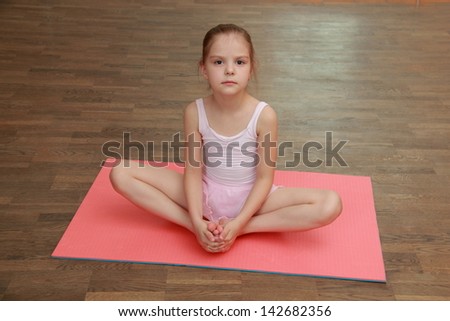 Little gymnast in a tracksuit and a gym shoes in gym class