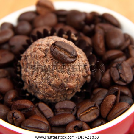 Full coffee cup and saucer of coffee beans with delicious chocolate candy on Food and Drink theme
