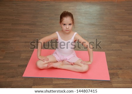 Little gymnast in a tracksuit and a gym shoes