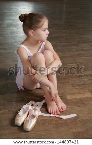 Young girl engaged in a pink ballet tutu and pointe in the ballet hall on the wooden dance floor