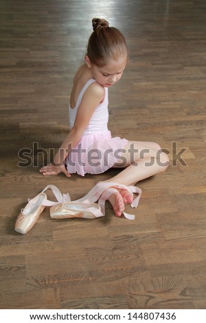 Caucasian lovely girl engaged in a pink ballet tutu and pointe in the ballet hall on the wooden dance floor