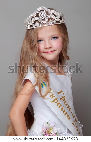Charming young girl in a white ball gown sweet smiles/Beautiful little girl in a white dress with ribbon and the words in Ukrainian \