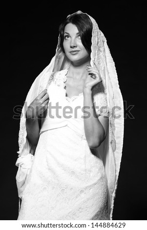 Black and white image of a beautiful young bride in a wedding dress on a black background