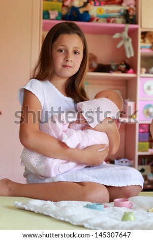 Caucasian girl playing with her baby doll and pretending mom