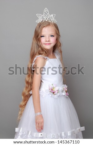 Charming young girl in a white ball gown sweet smiles
