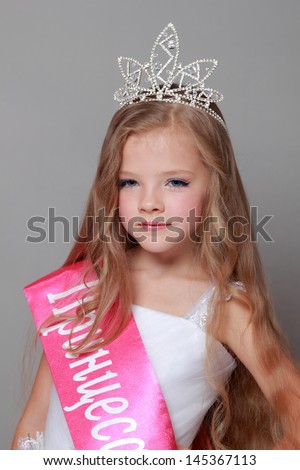 Girl with long blond hair in a white princess dress with a red ribbon and the word \