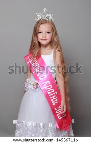 Little girl in princess dress with a red ribbon and the word \