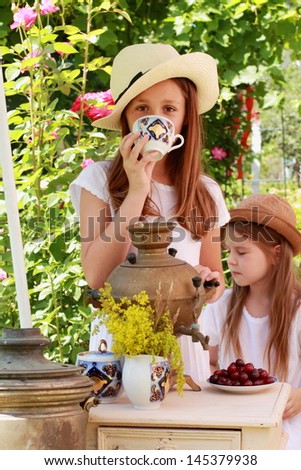 Children drink tea from an old Russian samovar in the garden in the street/Russian national traditions