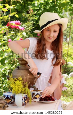 Caucasian girl drink tea from an old Russian samovar in the garden in the street/Russian national traditions