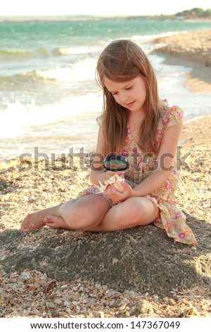 cute little girl holding a seashell/Young girl in a summer dress sitting on the beach and dreams