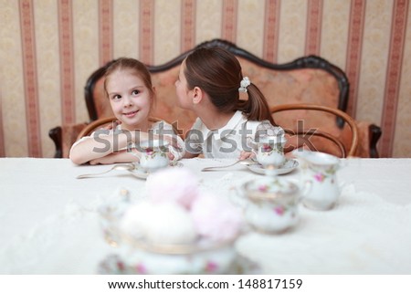 Caucasian little girls in white dress sitting at the dinner table and eat breakfast