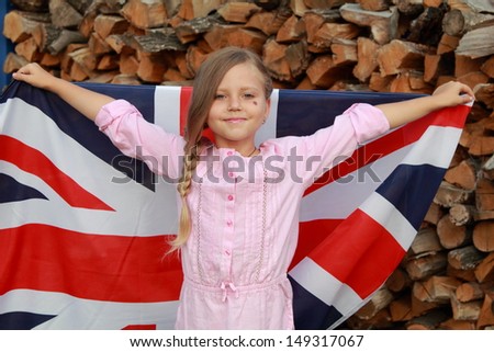 Joyful pretty young girl holding a big flag of Great Britain