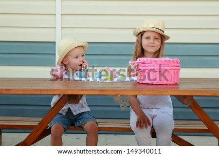 Funny little boy and girl brother and sister in a straw hat playing with toys outdoors in the summer